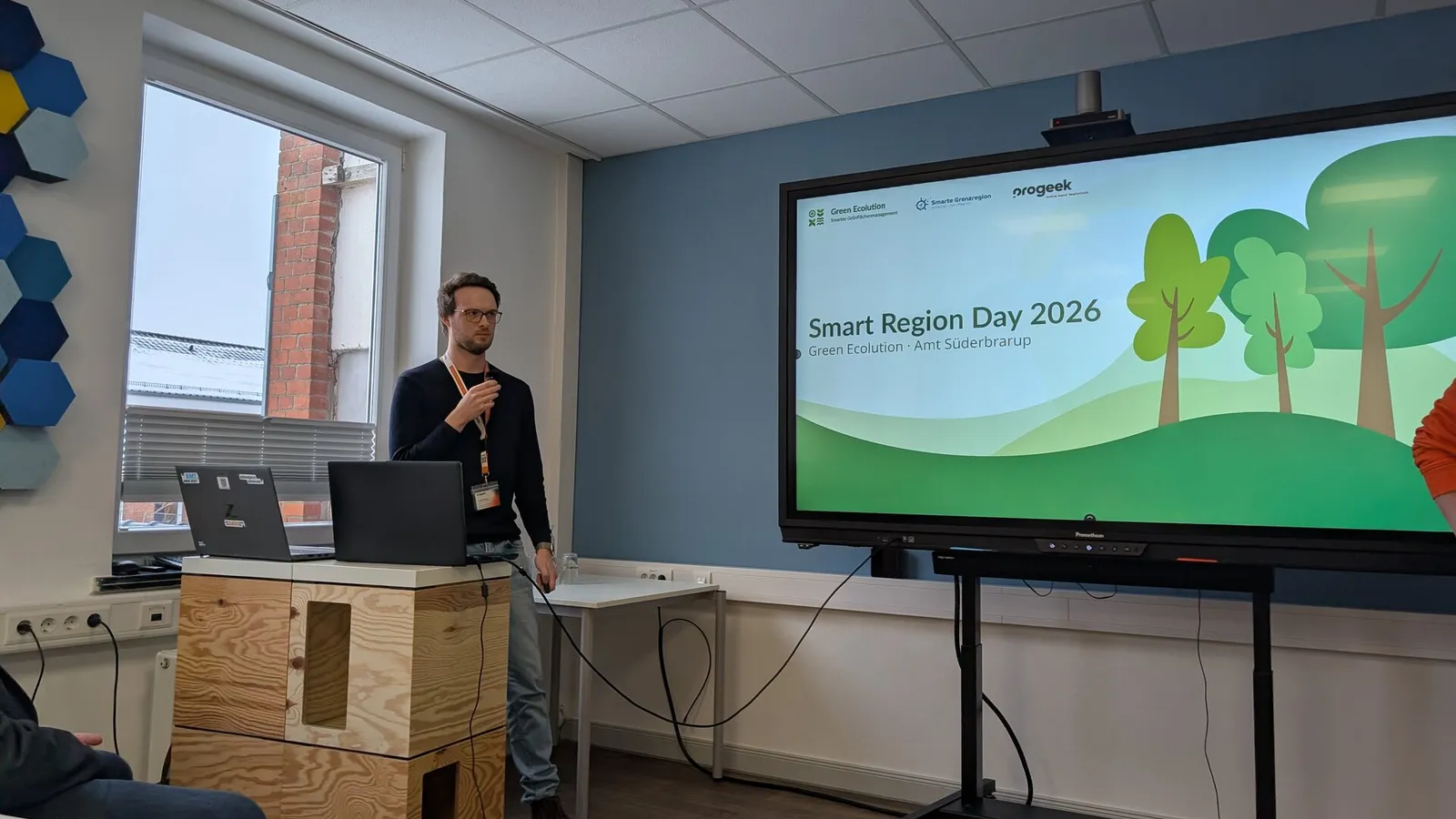 Cedrik Hoffmann hält einen Vortrag vor einem großen Bildschirm mit der Titelfolie Smart Region Day 2026 von Green Ecolution und Amt Süderbrarup